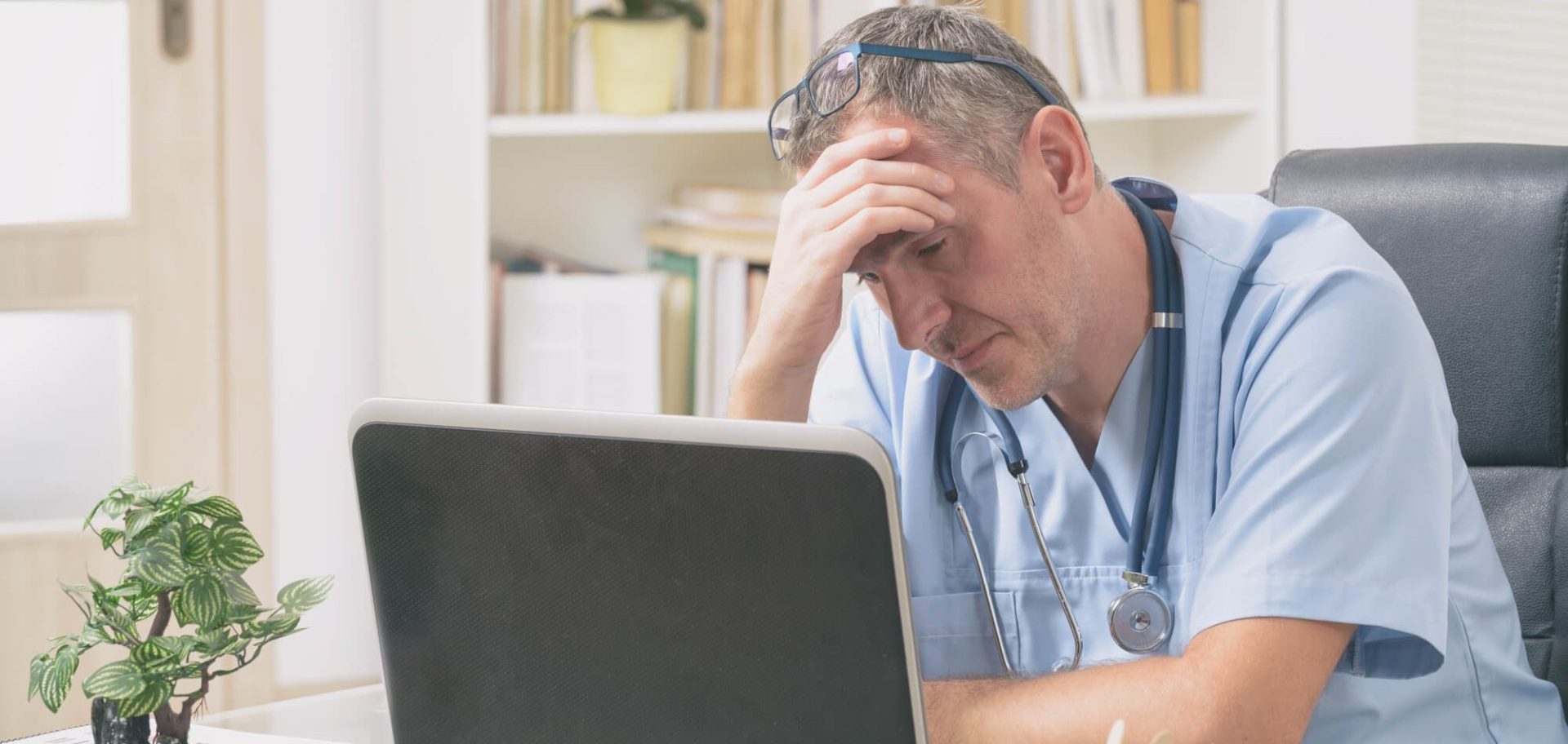 Doctor at Computer with Hand on Head