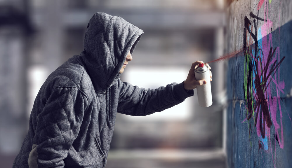Hooded Person Graffiti Tagging a Wall